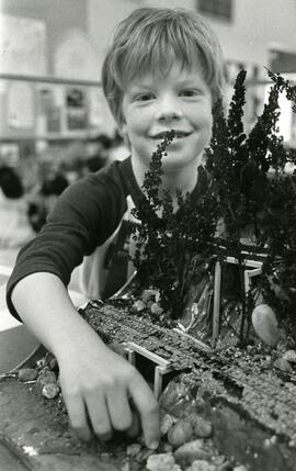 Boy posing with miniature train track model