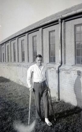 Man on crutches next to a warehouse