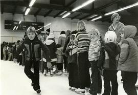 Kids line up in skating rink with parents