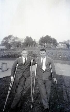 Two men on crutches standing in a yard