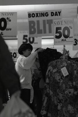 Shopper looking over sale items at Coquitlam Mall on boxing day