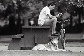 Blair Murray, sitting on a picnic table, reading, with his dog Kola, at Blue Mountain Park