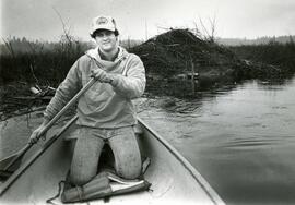 Man paddling his canoe past brush piles