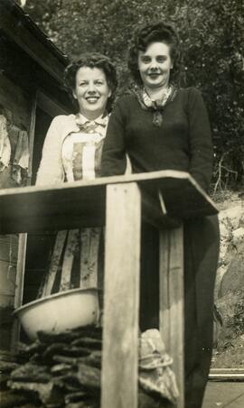 Two women standing on near a table outside