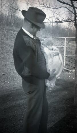 William Headridge holding a baby in a yard