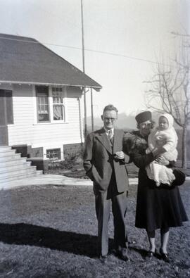 William Headridge and Ida May Headridge holding a baby in a yard