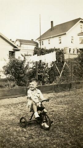 Brian Bovet riding a tricycle in a yard