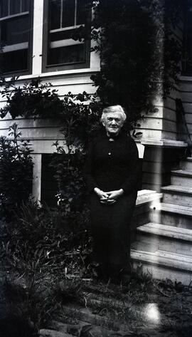 Old woman in front of likely Essondale Cottage 118
