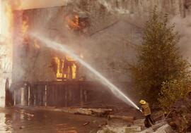 Firefighter spraying water on a building fire