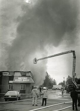 A large plume of smoke rises in the air from Metro Fords Body shop during a fire on Friday morning