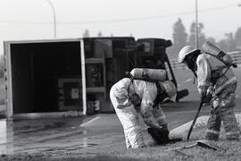 Truck accident on Brunette overpass at Highway 1 exit ramp, spilling hazardous chemicals on the road, causing traffic chaos