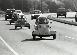 Several three wheeled Messerschmitt vehicles driving along Lougheed Highway