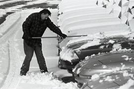 Metro Motors. Terry McDonald, Rick Lundsted and Bob McGuire all clean snow off cars with brooms and using snow blower on paths.
