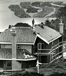 A roofer enjoys the view from atop a new home in Port Moody as log booms in Burrard Inlet await journey to the sawmill.