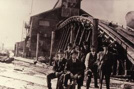 Men dressed in suits posing in front of Fraser Mills