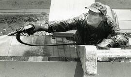 Barry Hunt uses a power washer to clean the crud off the cedar shingles
