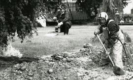 Gas leak Emergency Response team member Steve Breer digs down to gasline while his partner prepares a device to pinch off the line.