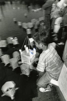 A young man launches his Peace lantern into Como Lake