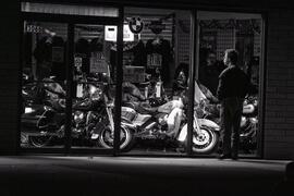 Man looking into Caribou Motorcycle shop, wishing for an early Xmas present