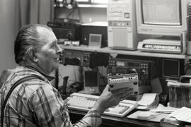 Roger Briggs communicating through a hand-held modem linked up to his ham radio