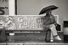 Tour shot of lady in the rain at bus stop