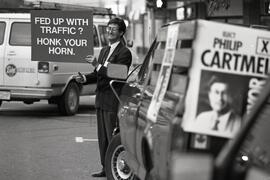 Mayor candidate Phil Cartmel in front of City Hall with his sign depicting lousy transportation
