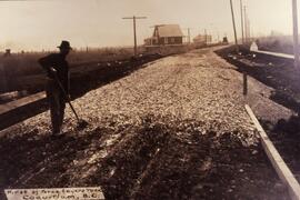 Man raking gravel on a road