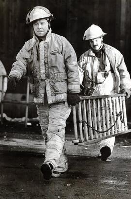 Coquitlam firefighters Erik Visscher (front) and Tom Boechler return ladder to its truck Monday afternoon after Fraser Mills fire on Sunday